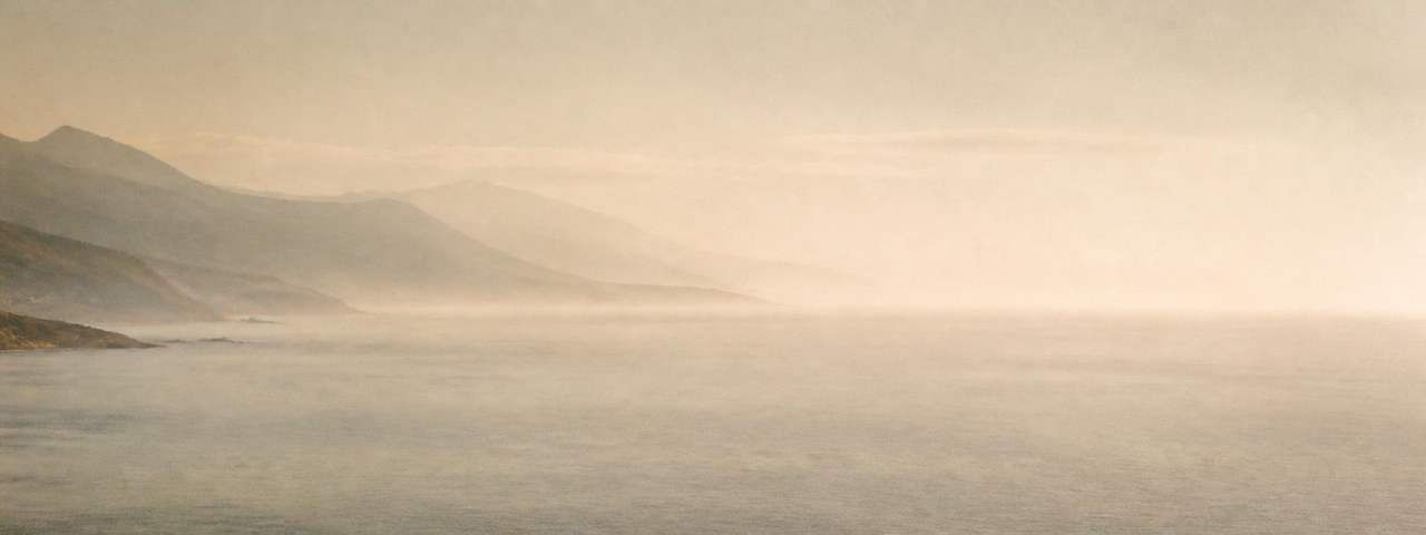 Soft dawn mist over a calm coastal horizon